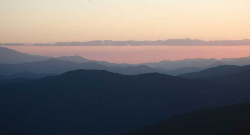 The sky appears in gentle colors above mountains that appear blue
